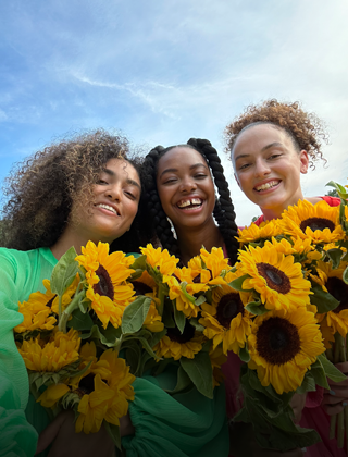 Selfie net et éclatant de trois personnes tenant des fleurs.